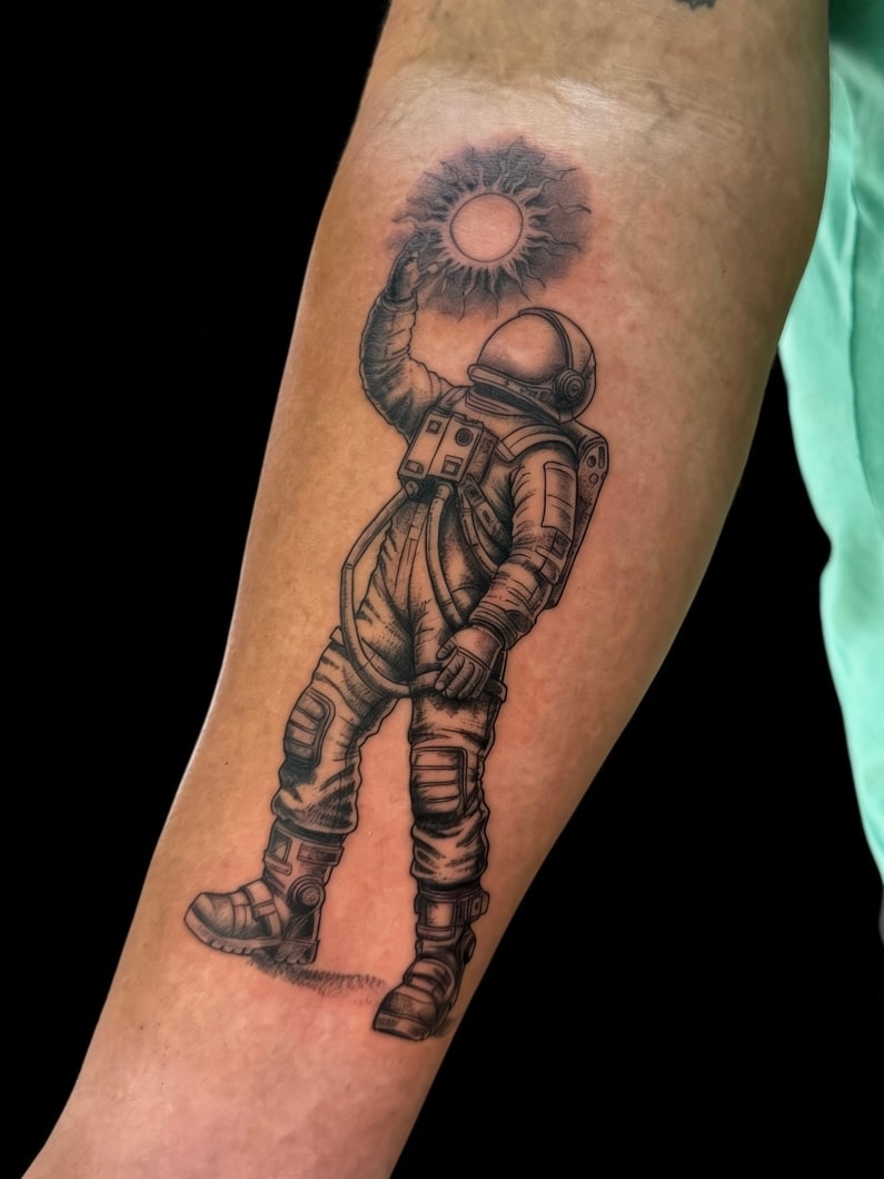 Tatuaje blackwork de astronauta y sol