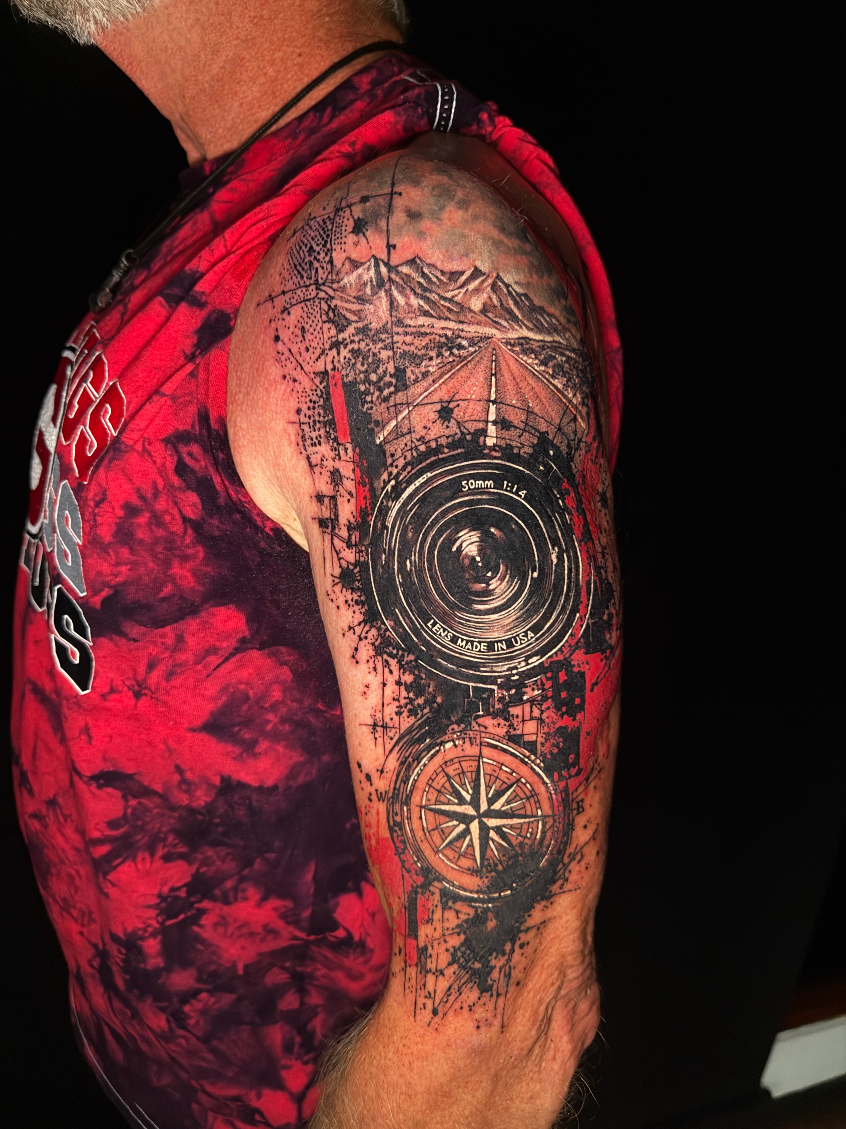 Tatuaje estilo libre de lente de cámara y brújula en el brazo