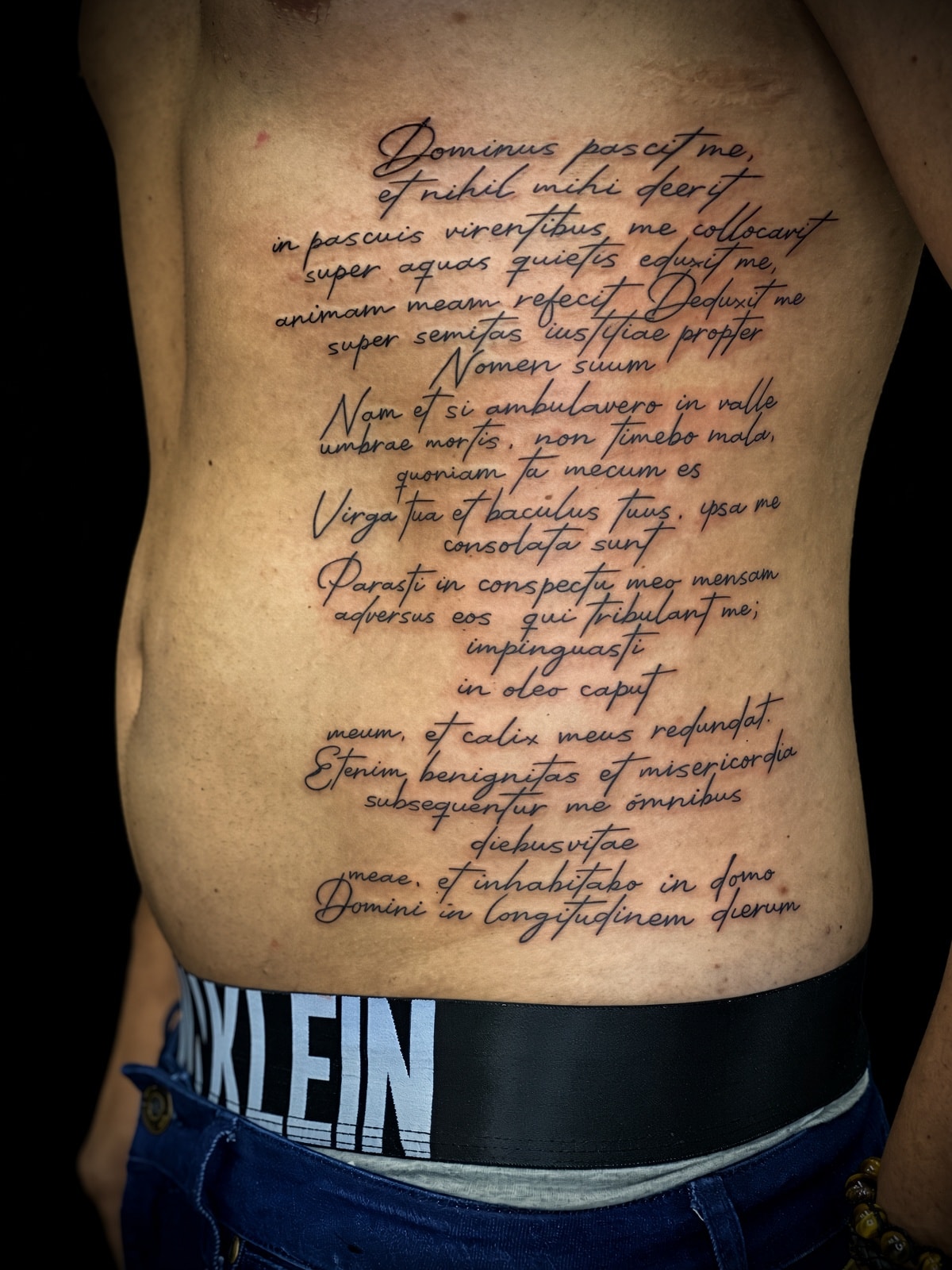 Tatuaje lettering salmo en latín en el torso