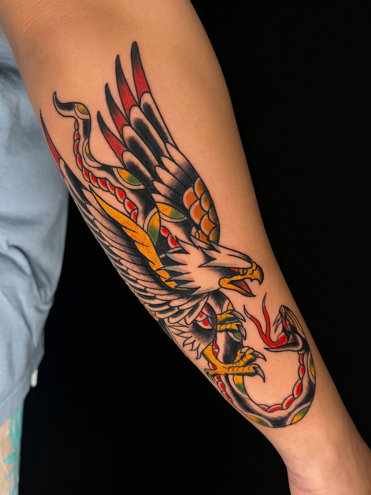 Tatuaje old school de águila con serpiente en antebrazo