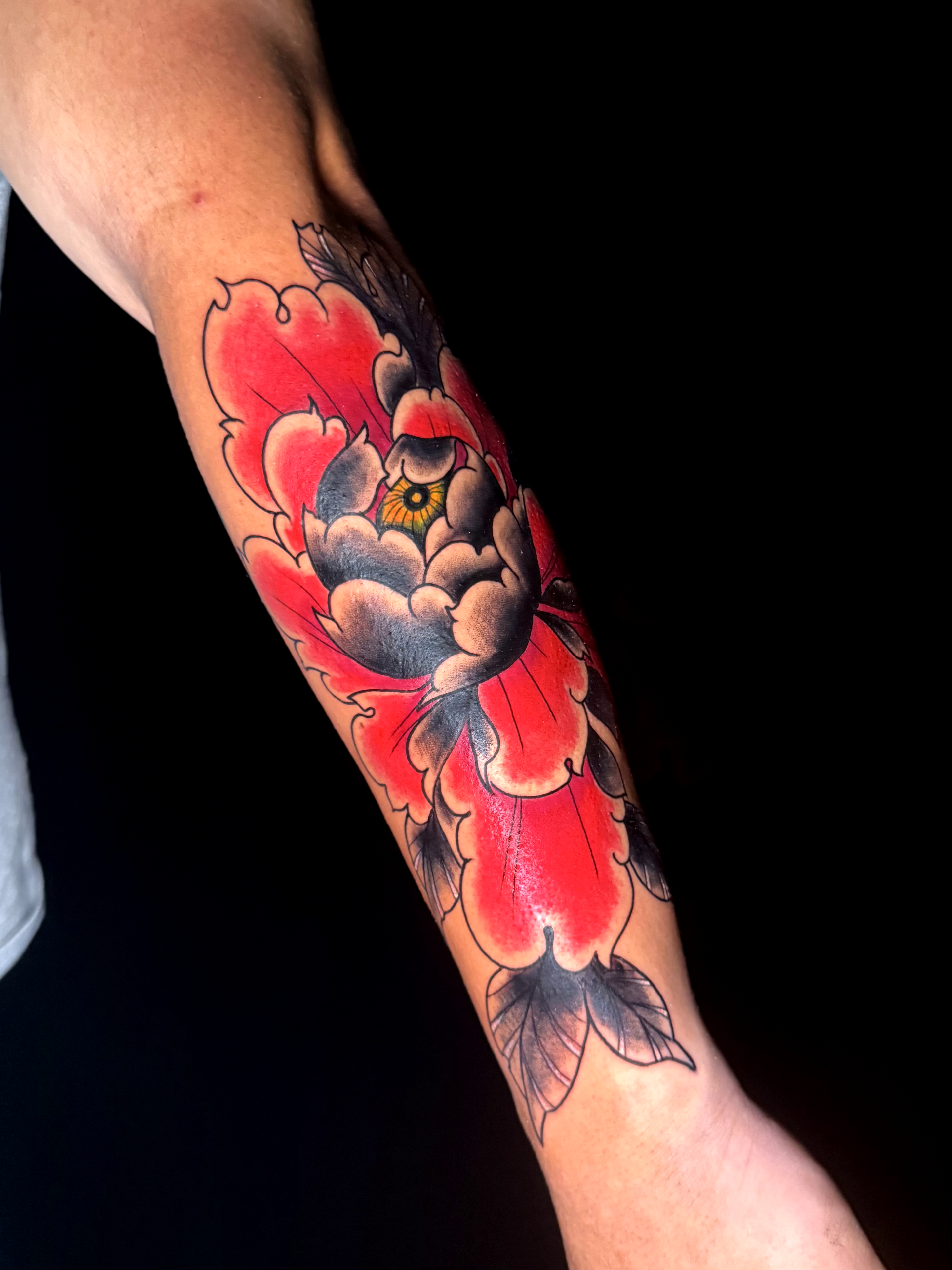 Tatuaje old school de peonía roja en antebrazo