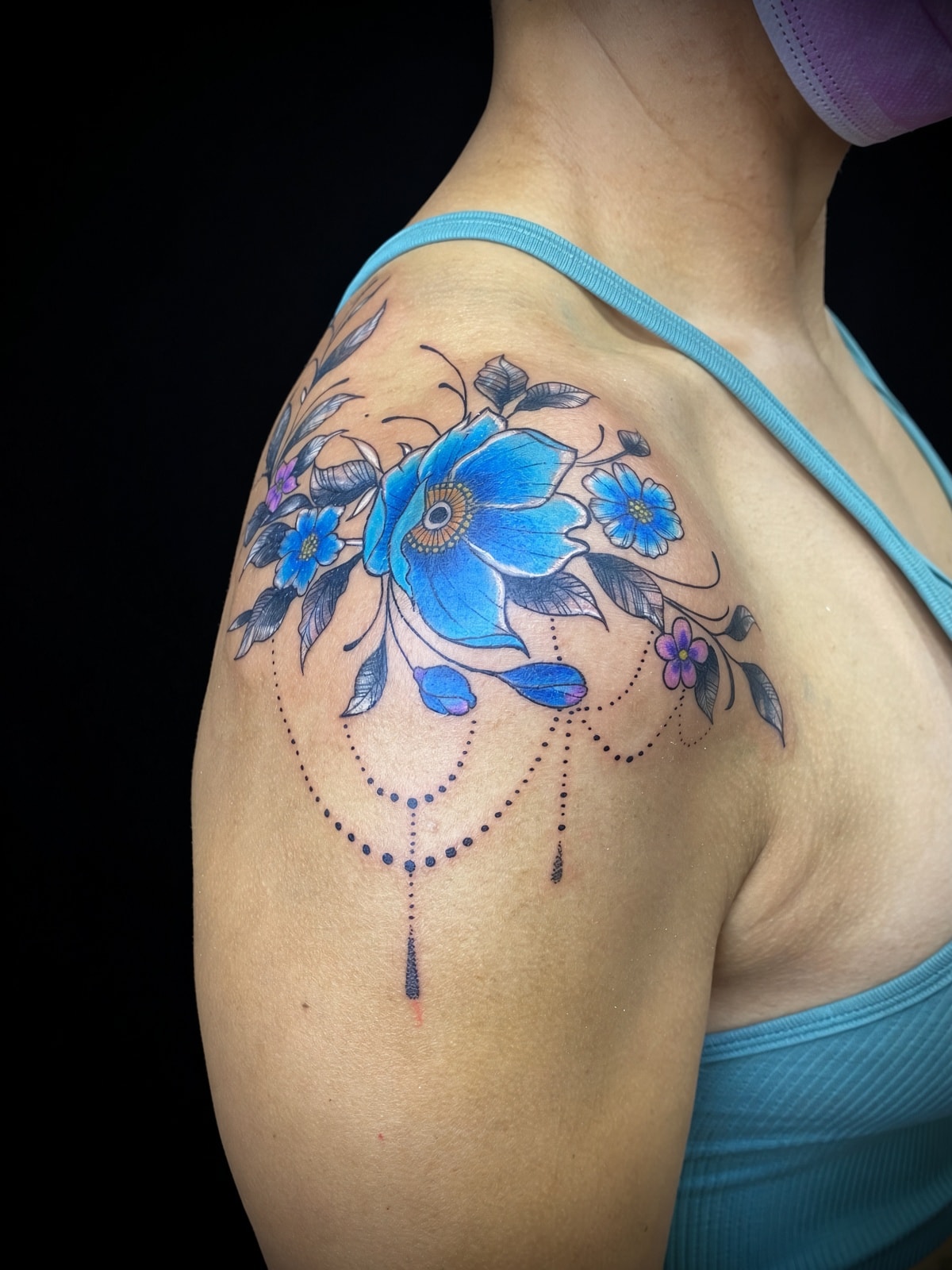 Tatuaje ornamental floral azul con cadenas en hombro