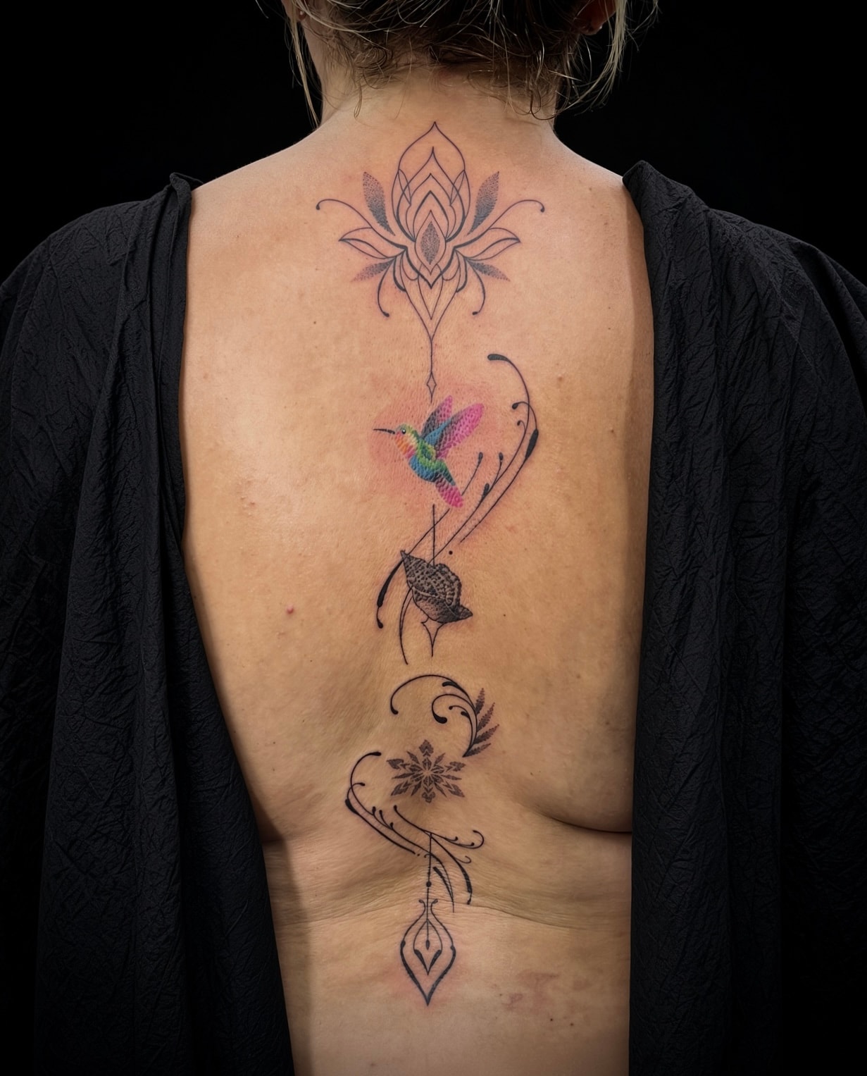Tatuaje ornamental de colibrí y flores en espalda