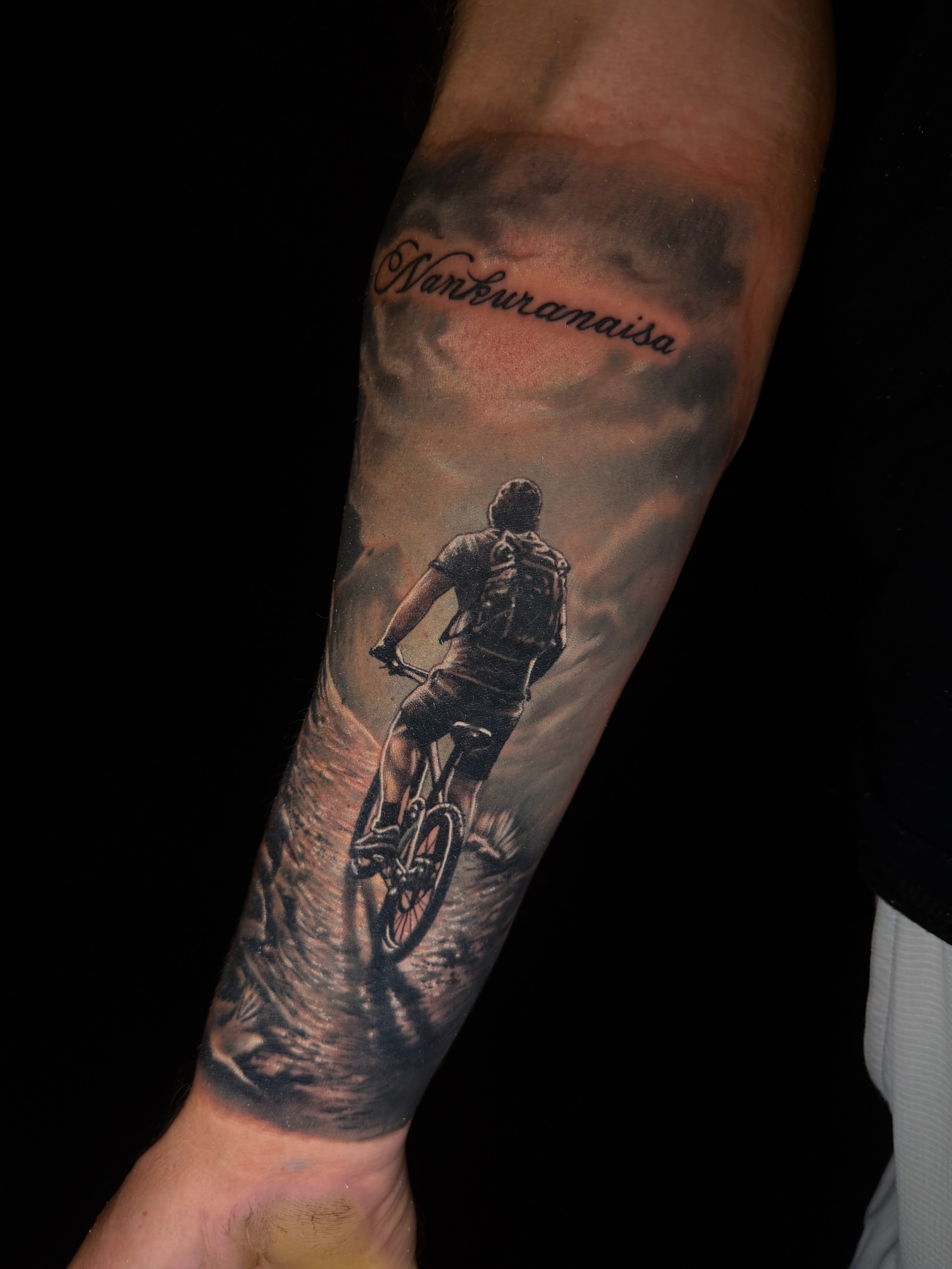 Tatuaje realista de ciclista en el antebrazo