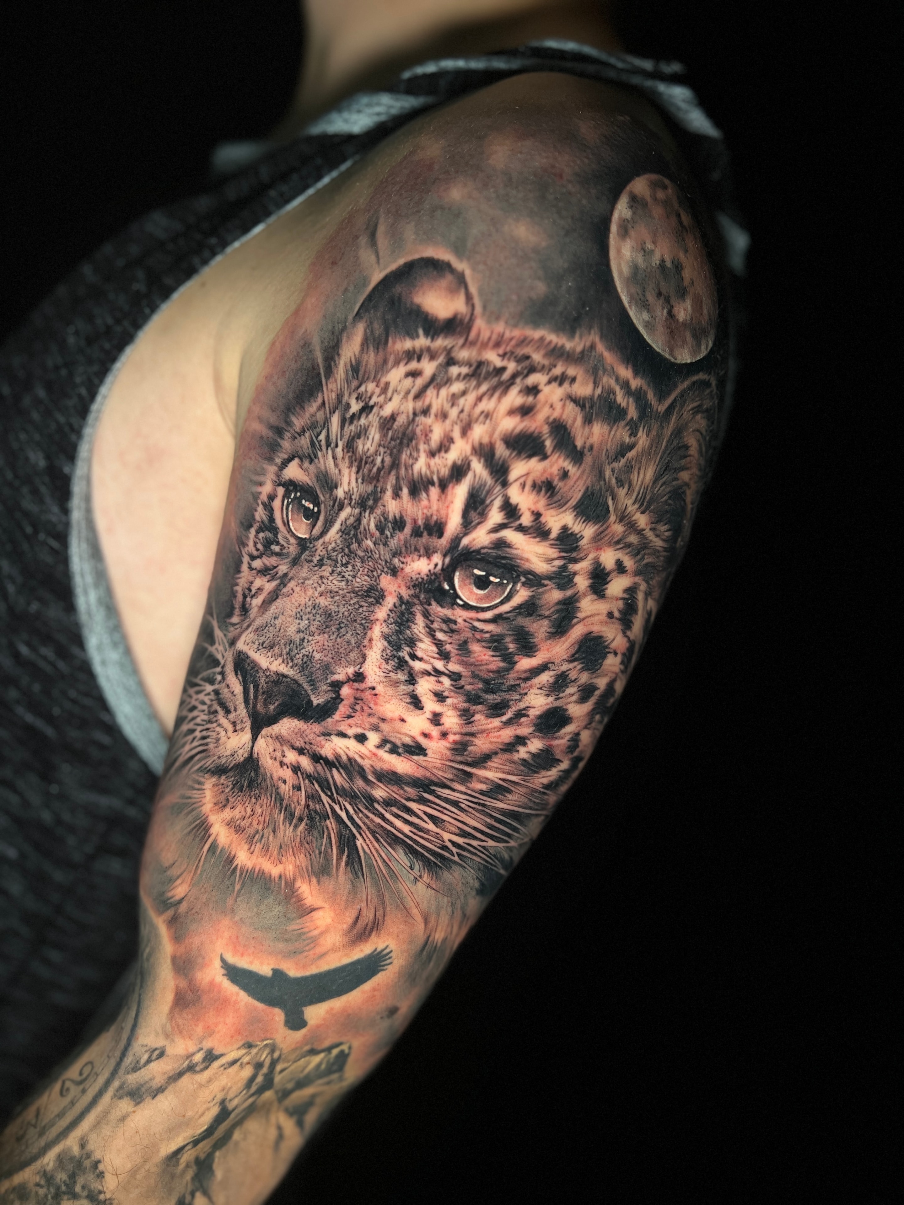Tatuaje realista de leopardo y luna en el brazo