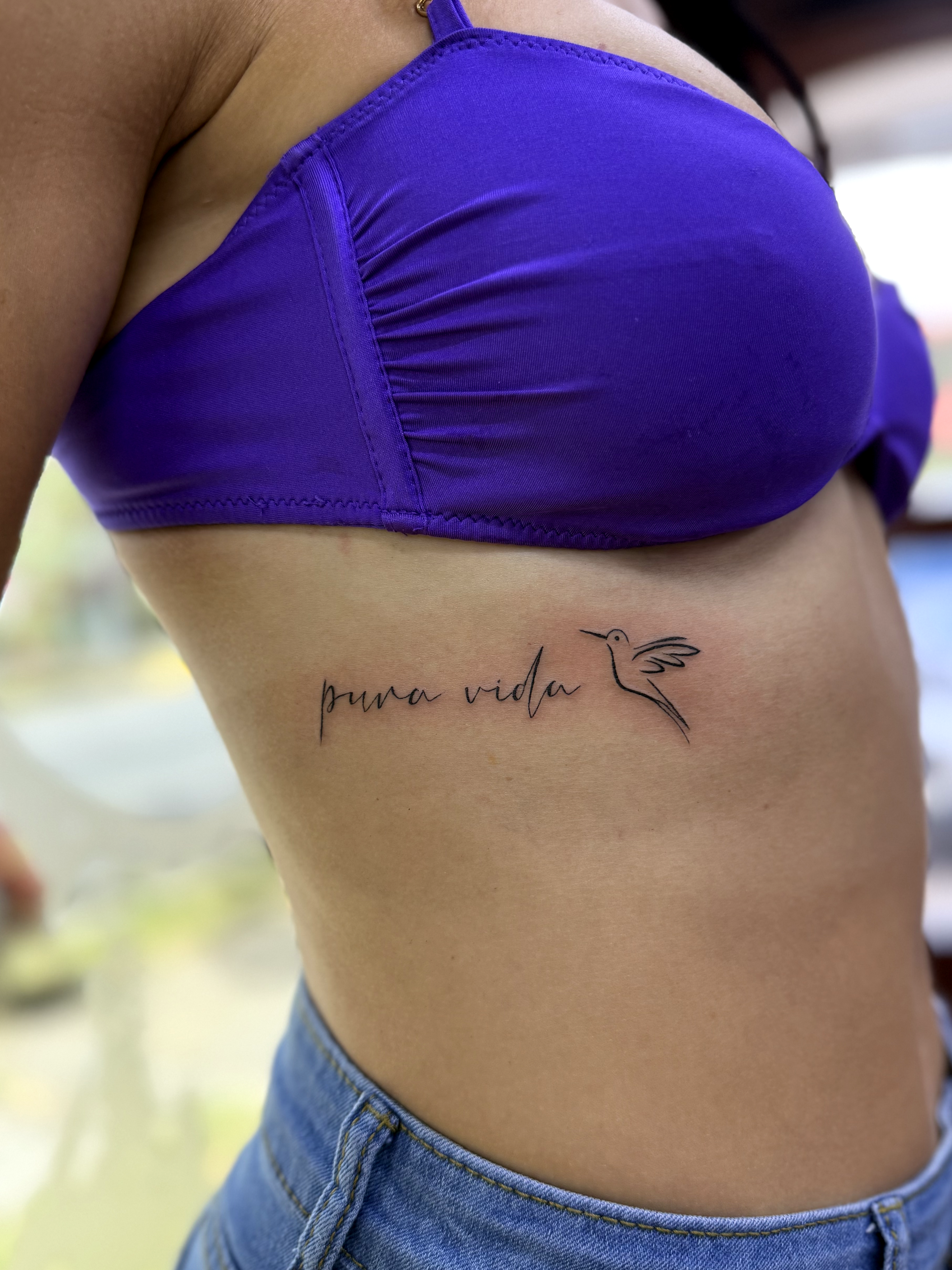 Tatuaje pura vida con colibrí en costillas — JP Tattoo Company San José